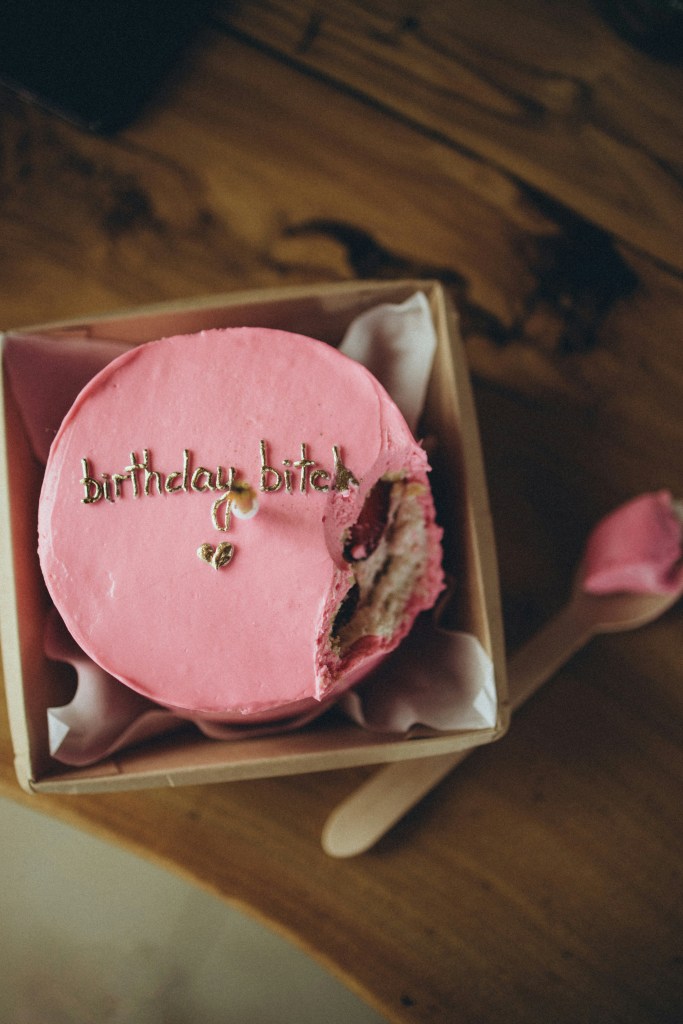 Pink birthday cake with "Birthday Bitch" written on it.